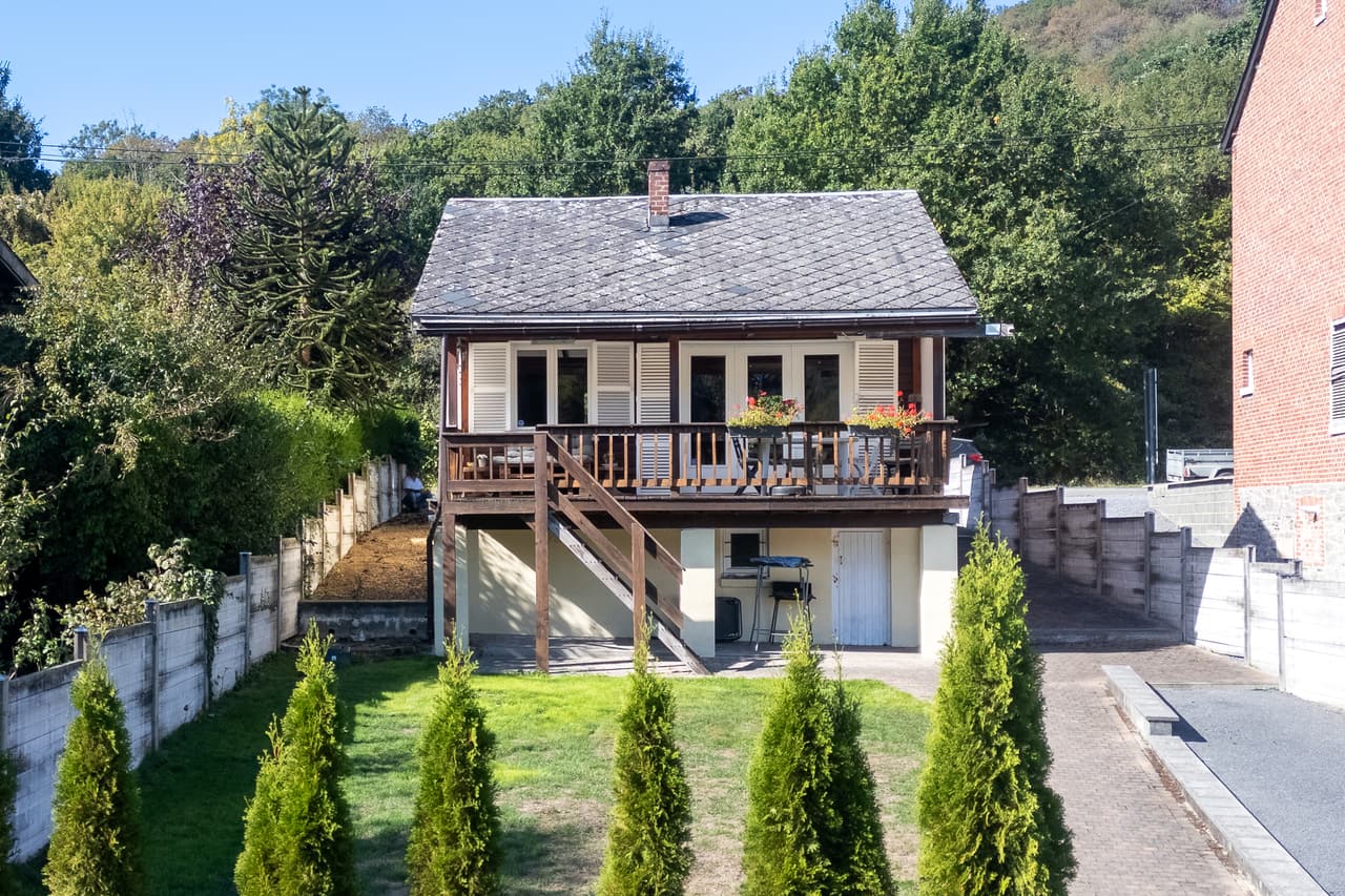 Gevel van het chalet vanuit de tuin, haag en trap
