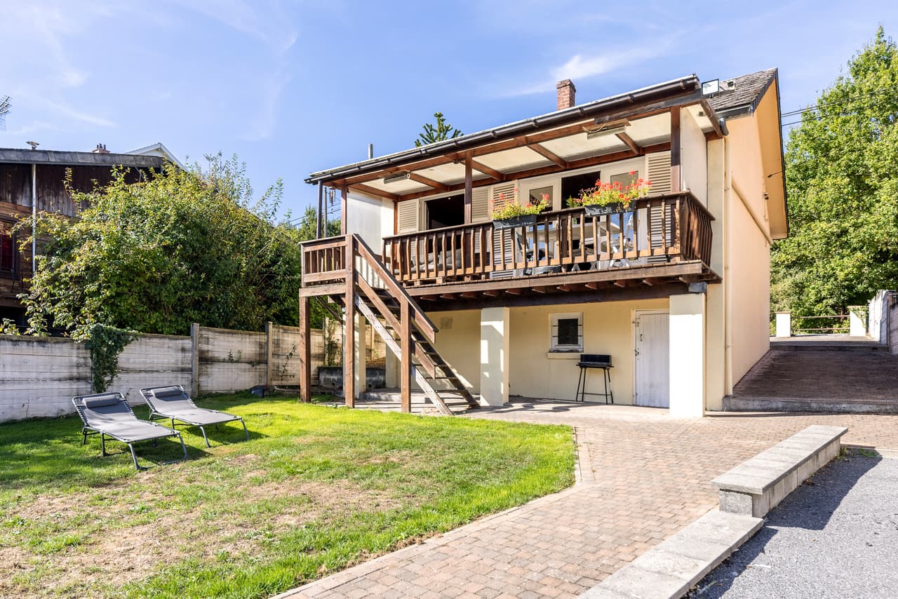 Gevel van het chalet, balkon, trap en tuin