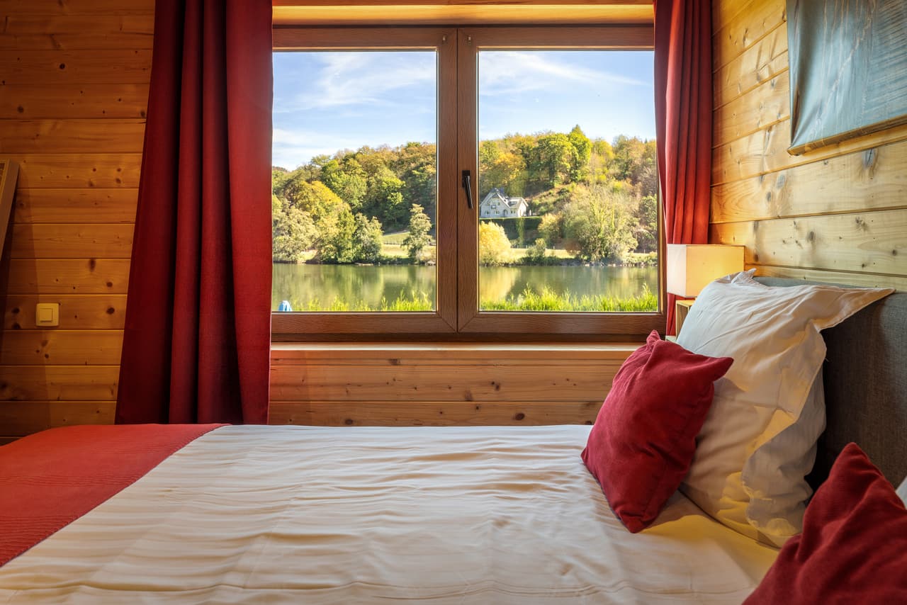 Raam van de slaapkamer op de Maas, tussen de rode gordijnen