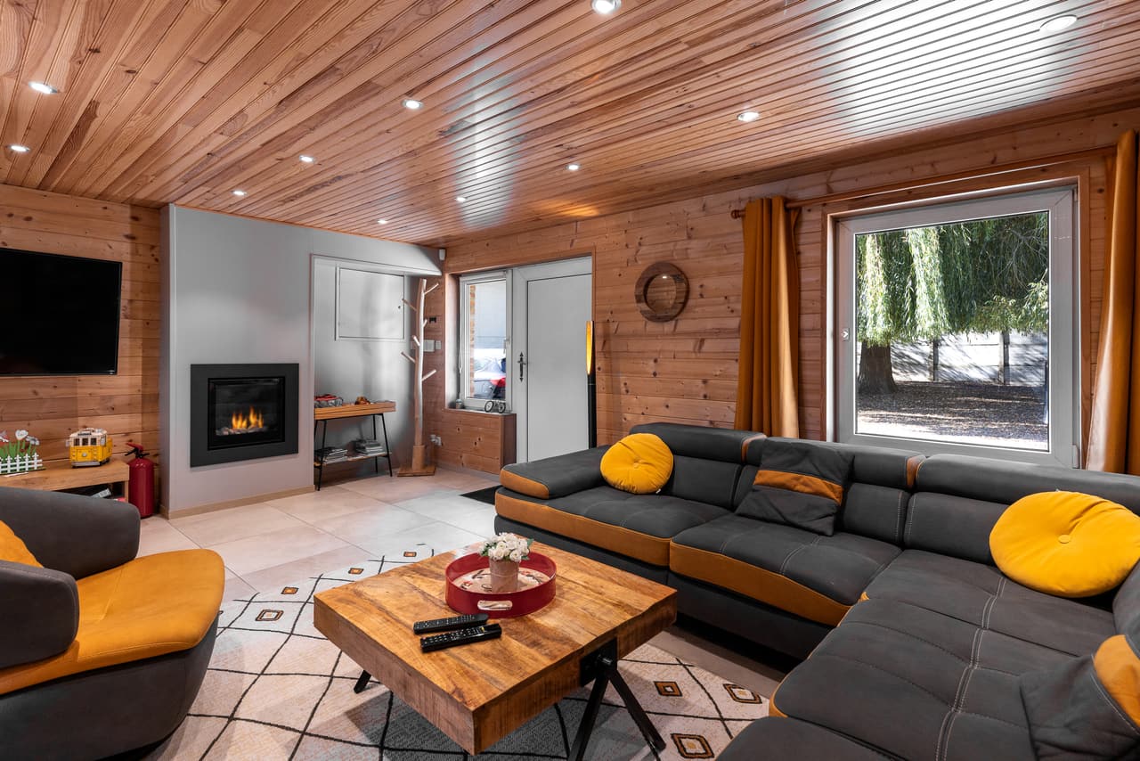 Woonkamer met inbouwhaard, donkere zitbank en raam