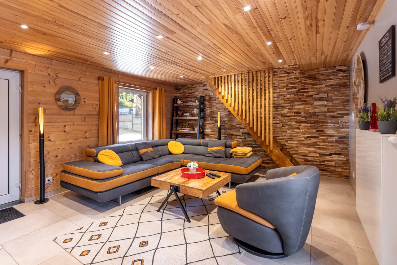 Woonkamer met hoekbank, fauteuil en houten trap