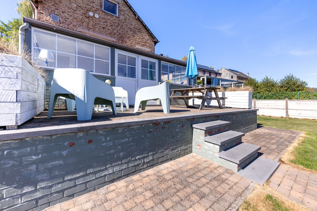 Verhoogd terras met stoelen en tafel, langs de veranda