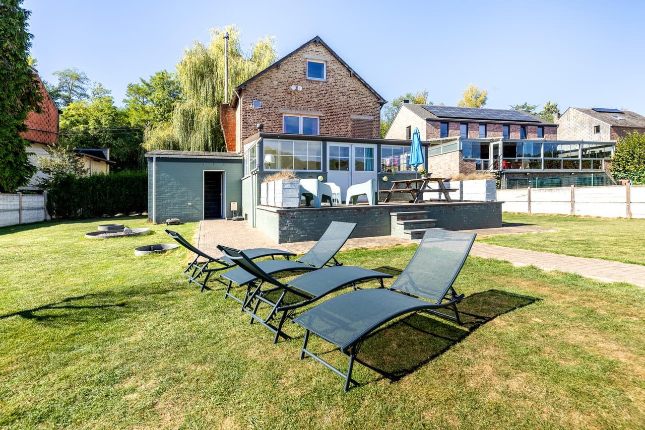 Ligstoelen en glazen gevel gezien vanuit de tuin