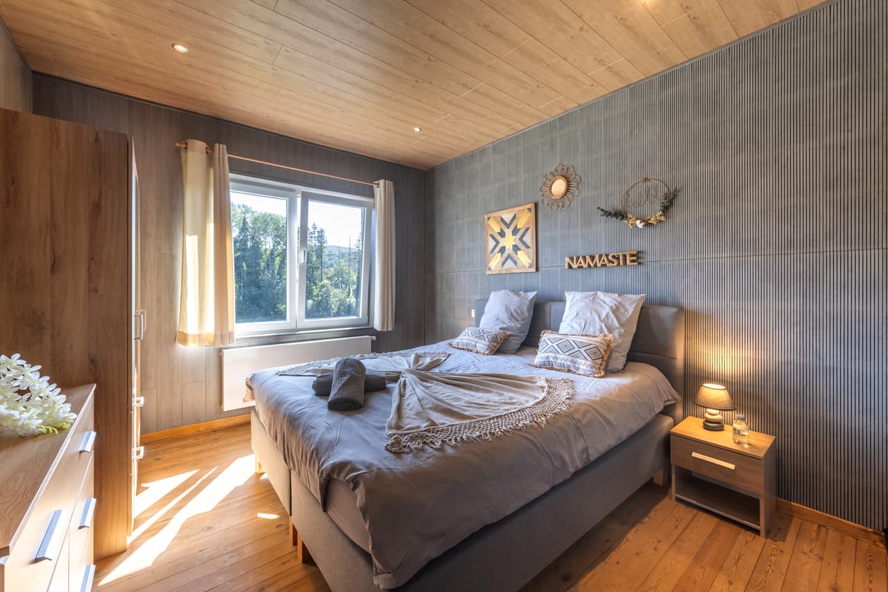 Grijze slaapkamer met groot bed en raam op de bomen