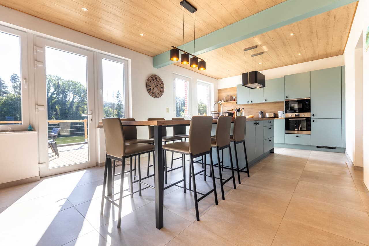 Keuken met grote tafel, krukken en glazen deuren naar het terras