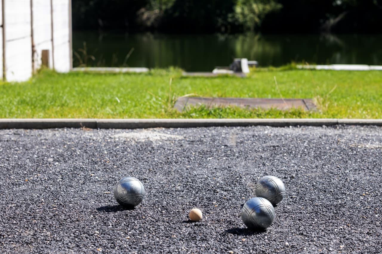 Jeu-de-boulesballen op de voorgrond, de Maas achter de baan