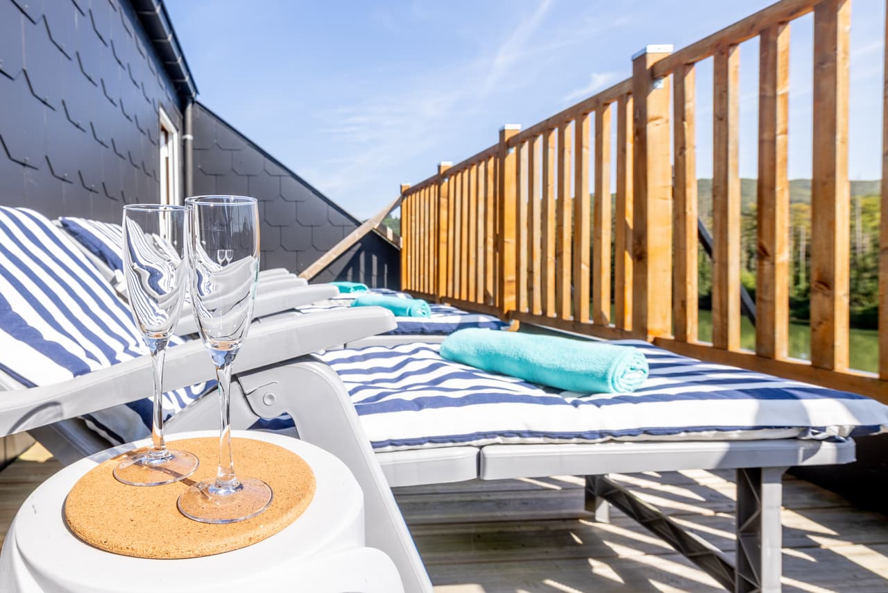 Ligstoel op het zonneterras met twee glazen, met uitzicht op de Maas
