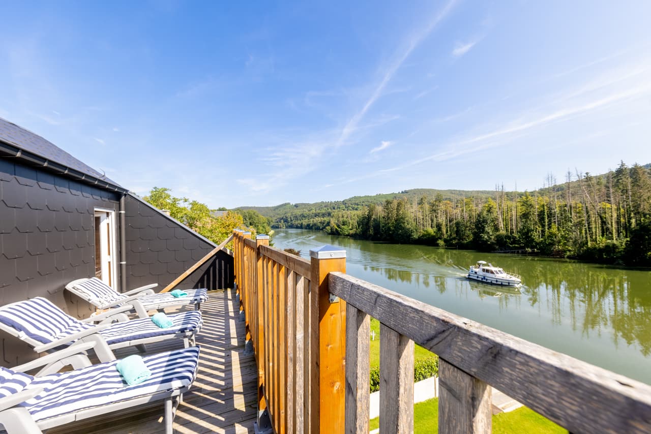 Zonneterras als een balkon boven de Maas, met een boot in de verte