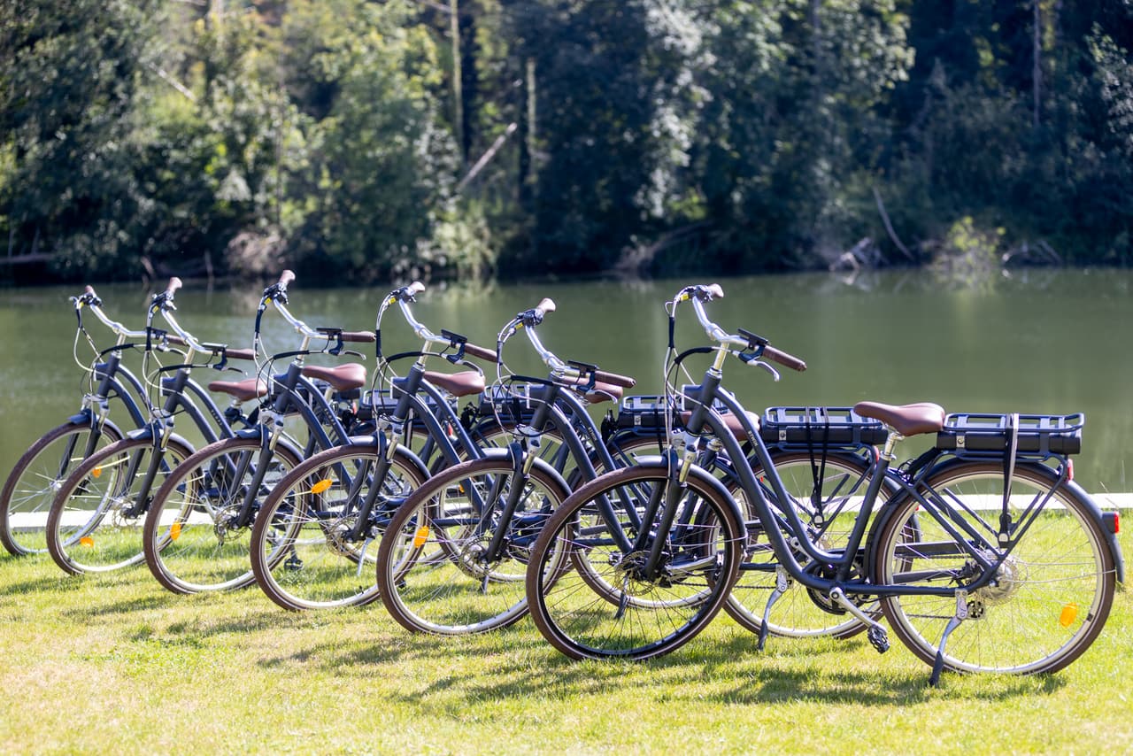 Rij elektrische fietsen op het gazon, tegenover de Maas